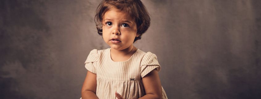 Bebé de un año sentada y con fondo gris
